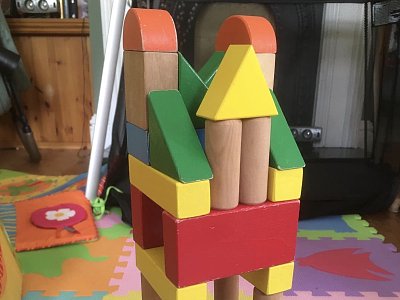 A tower of toy wooden bricks of different colours and shapes